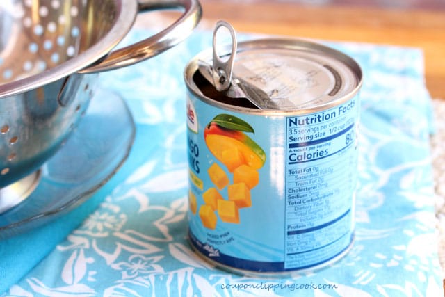 Open lid on can of cut mangos