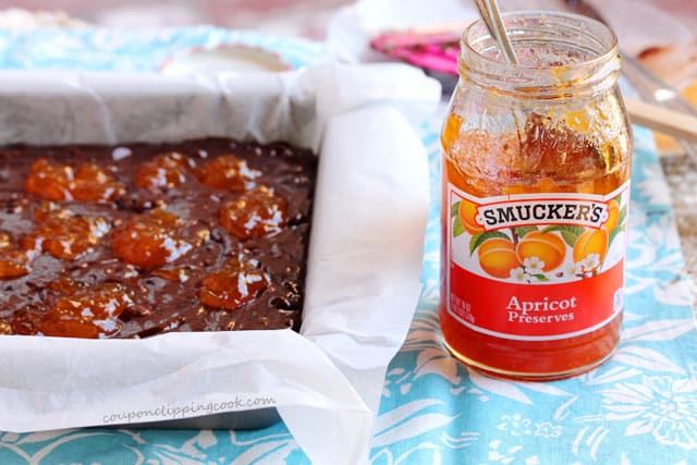Brownie batter in pan next to jar of jam