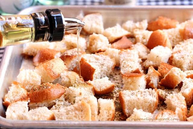Drizzle olive oil on cut bread in pan